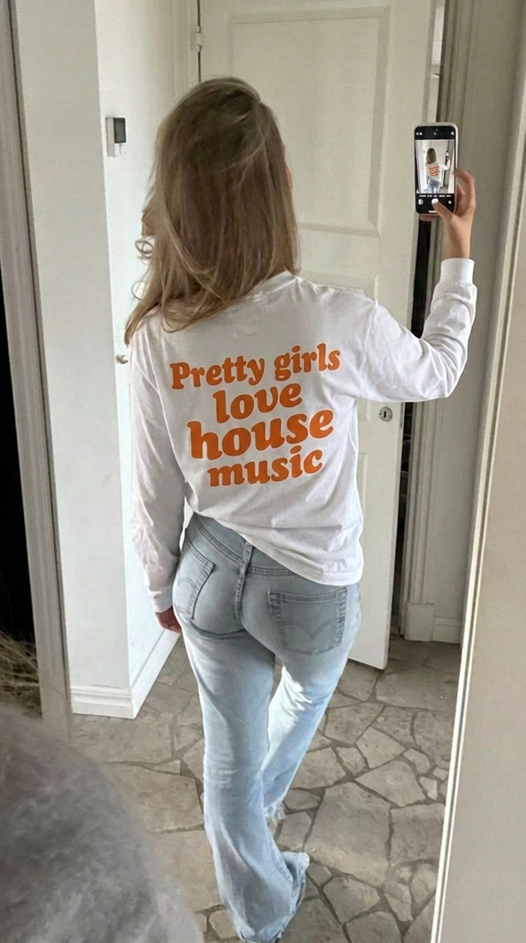 Witte longsleeve met oranje 'Pretty girls love house music' rugprint en lichte jeans — festival Koningsdag look